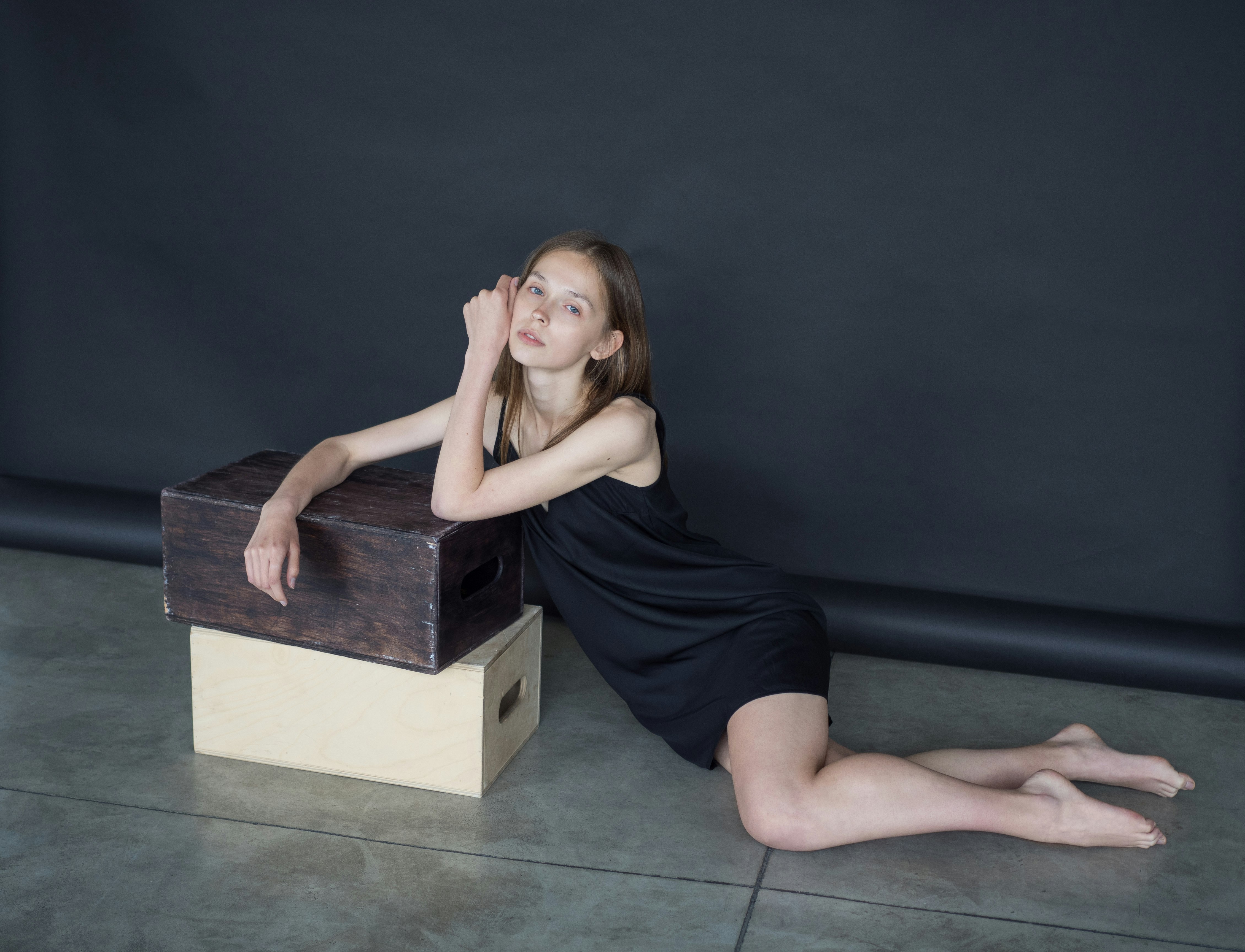 woman in black tank top and blue denim shorts sitting on black wooden box